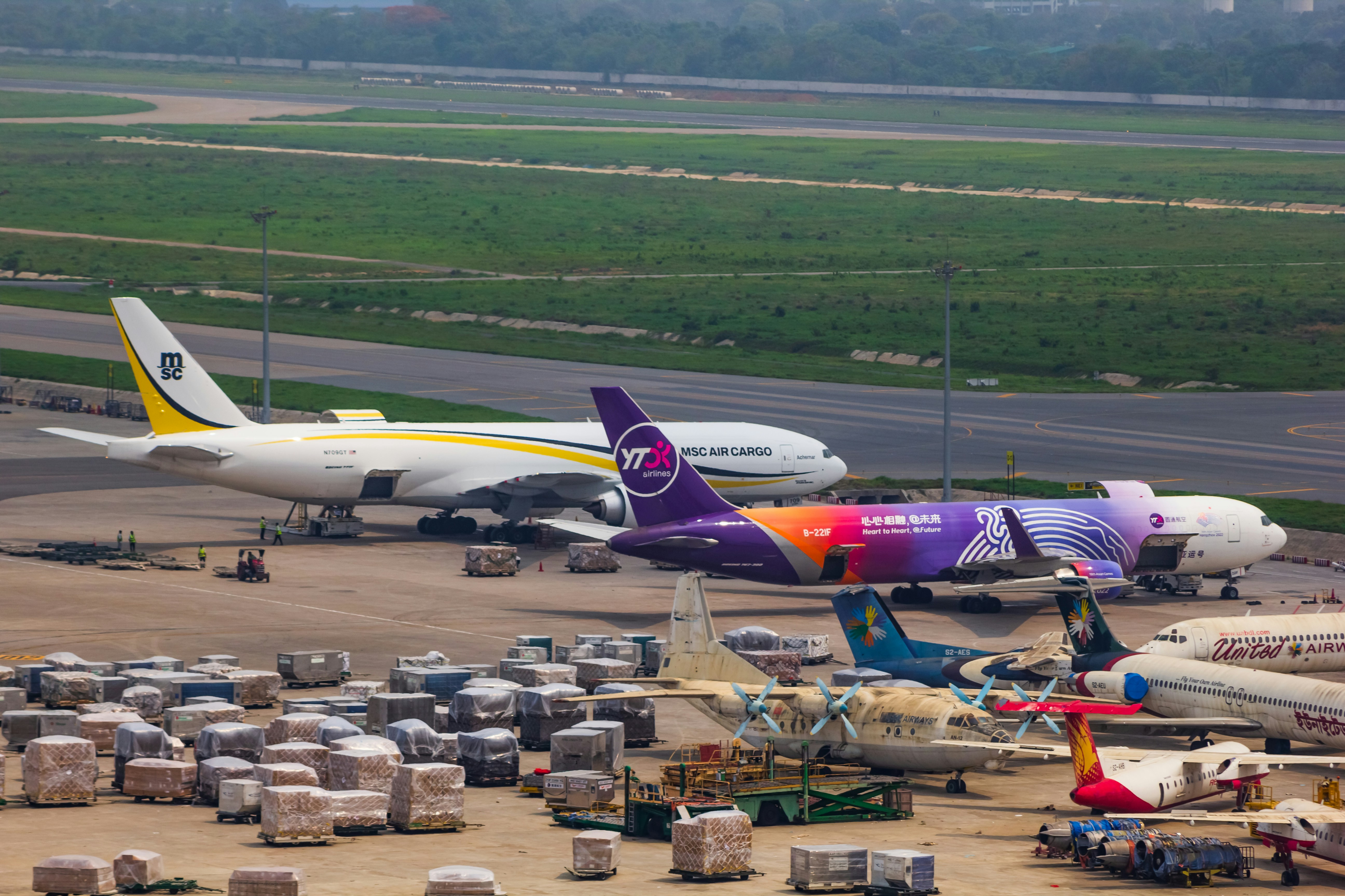 a couple of planes that are on a runway, Two aircrafts unloading cargo in Dhaka.