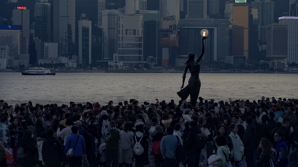 a crowd of people standing next to a body of water