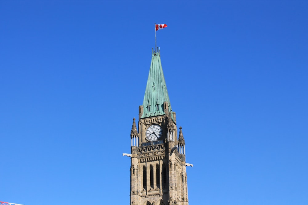 una alta torre de reloj con una bandera en la parte superior