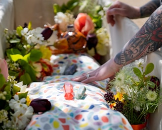 a spiritual farewell, body wraped in a colourful shroud, cystals and  flowers in the coffin
