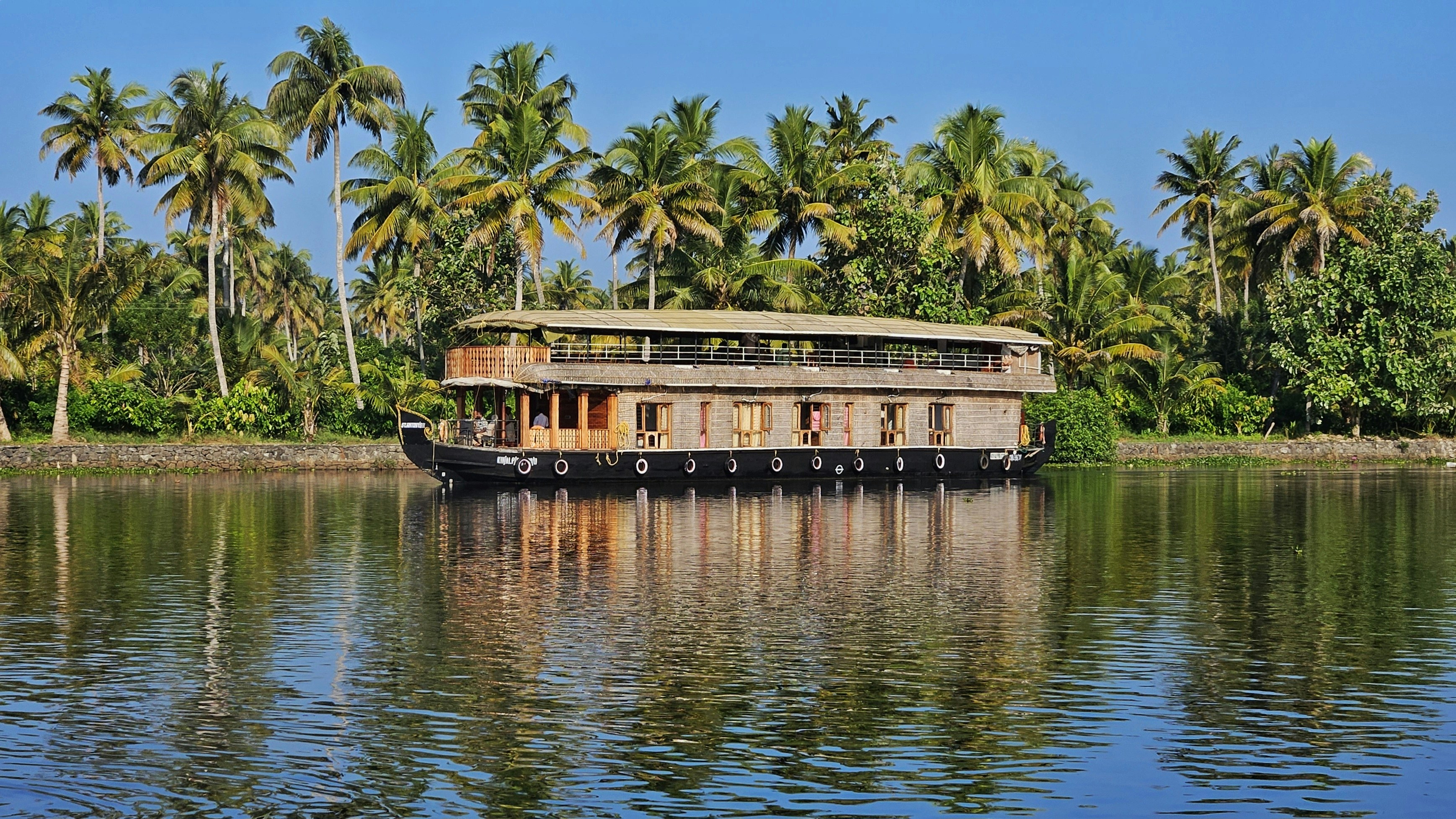 a house boat on a river with palm trees in the background
