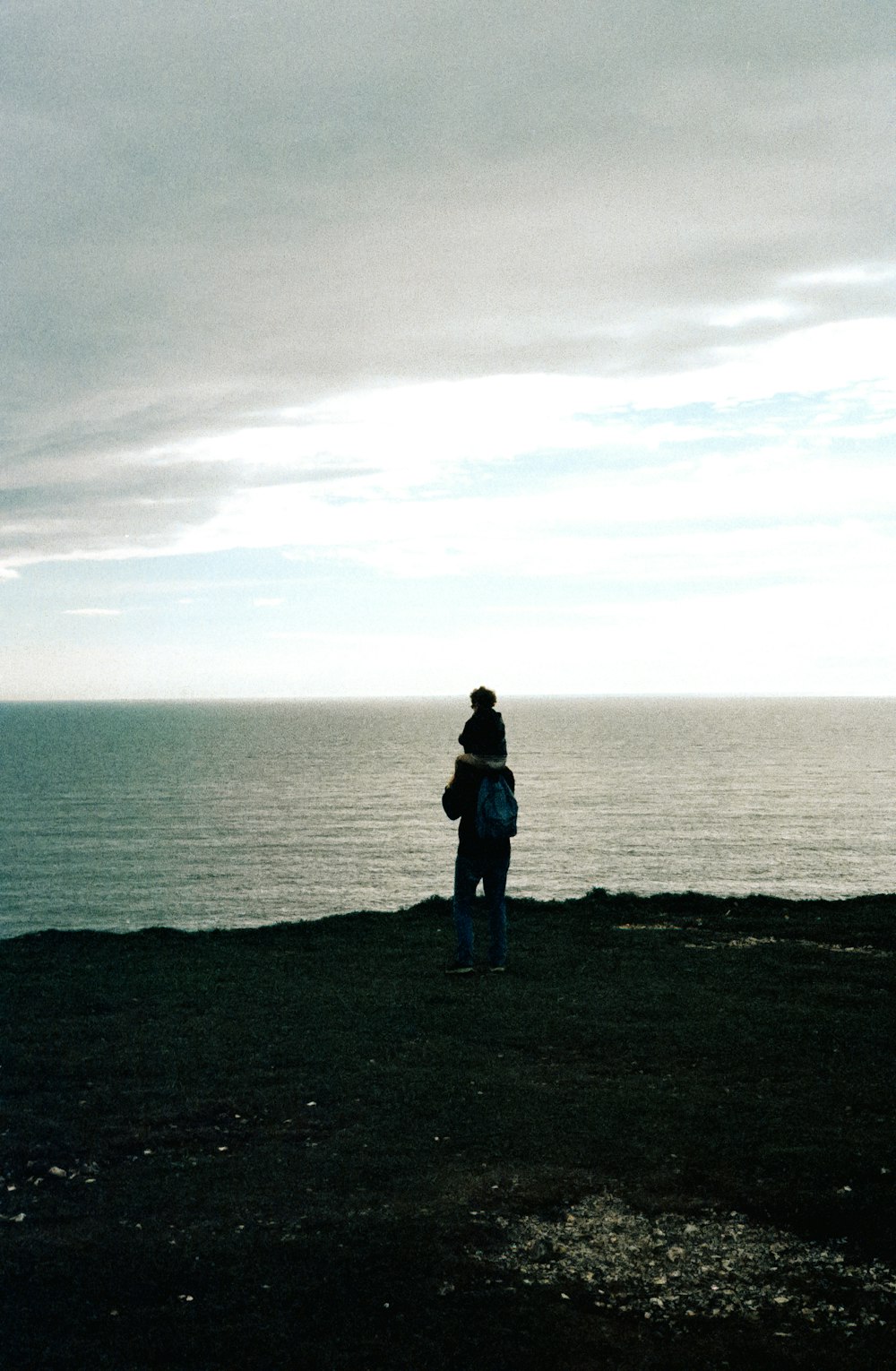 a person standing on top of a hill near the ocean