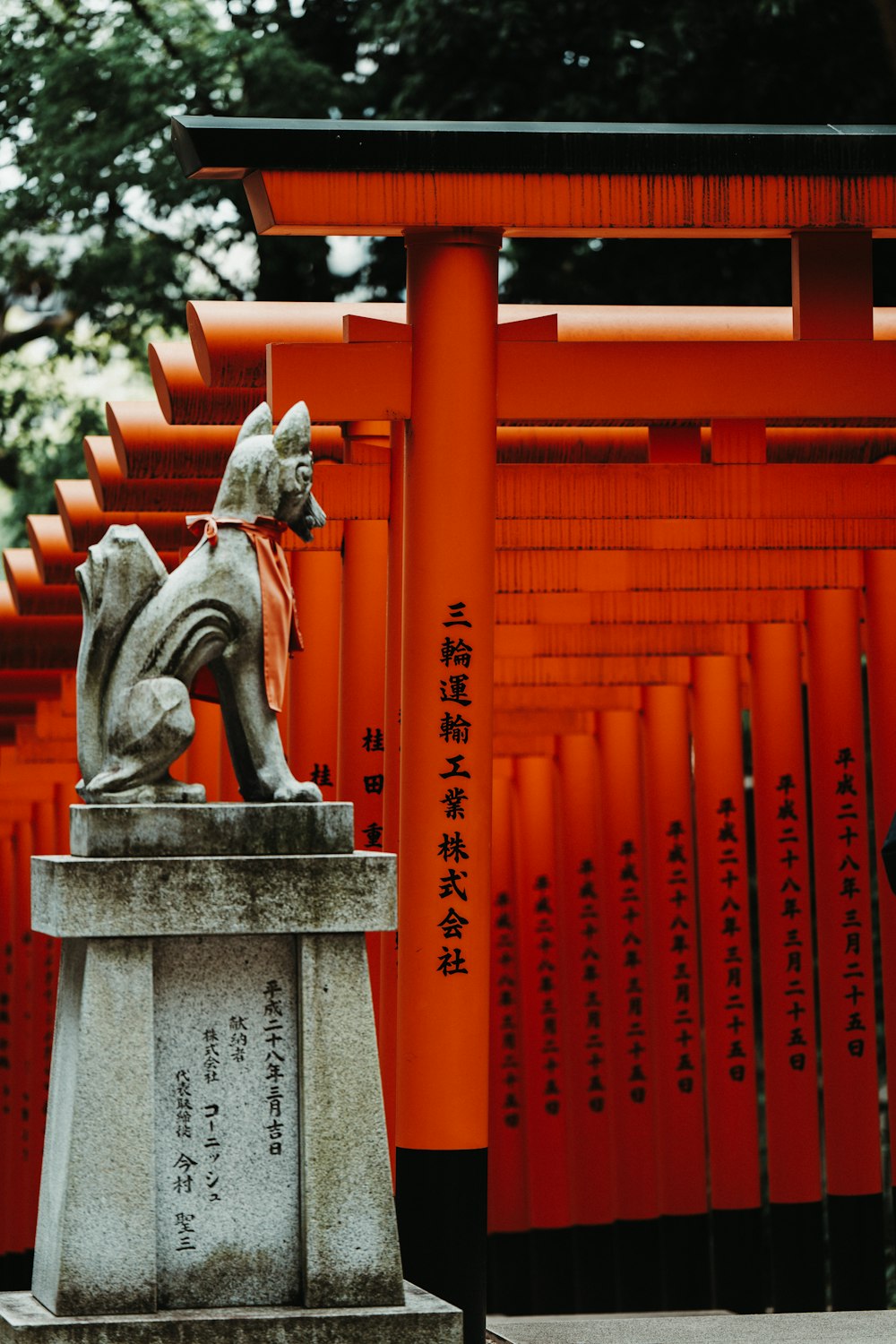 a statue of a dog in front of a row of red tori tori tori tori