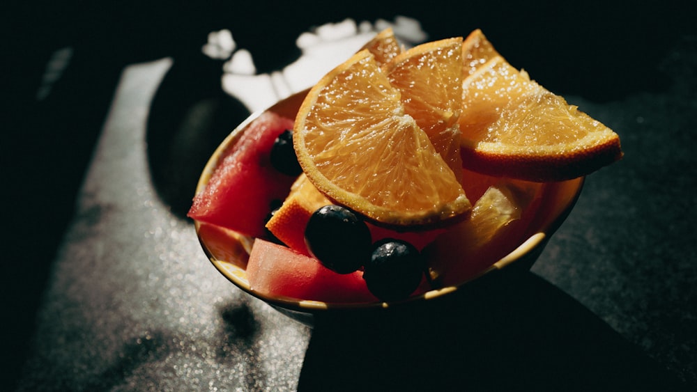 a bowl of fruit with oranges, blueberries, and watermelon