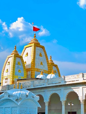 a white and gold building with a red flag on top
