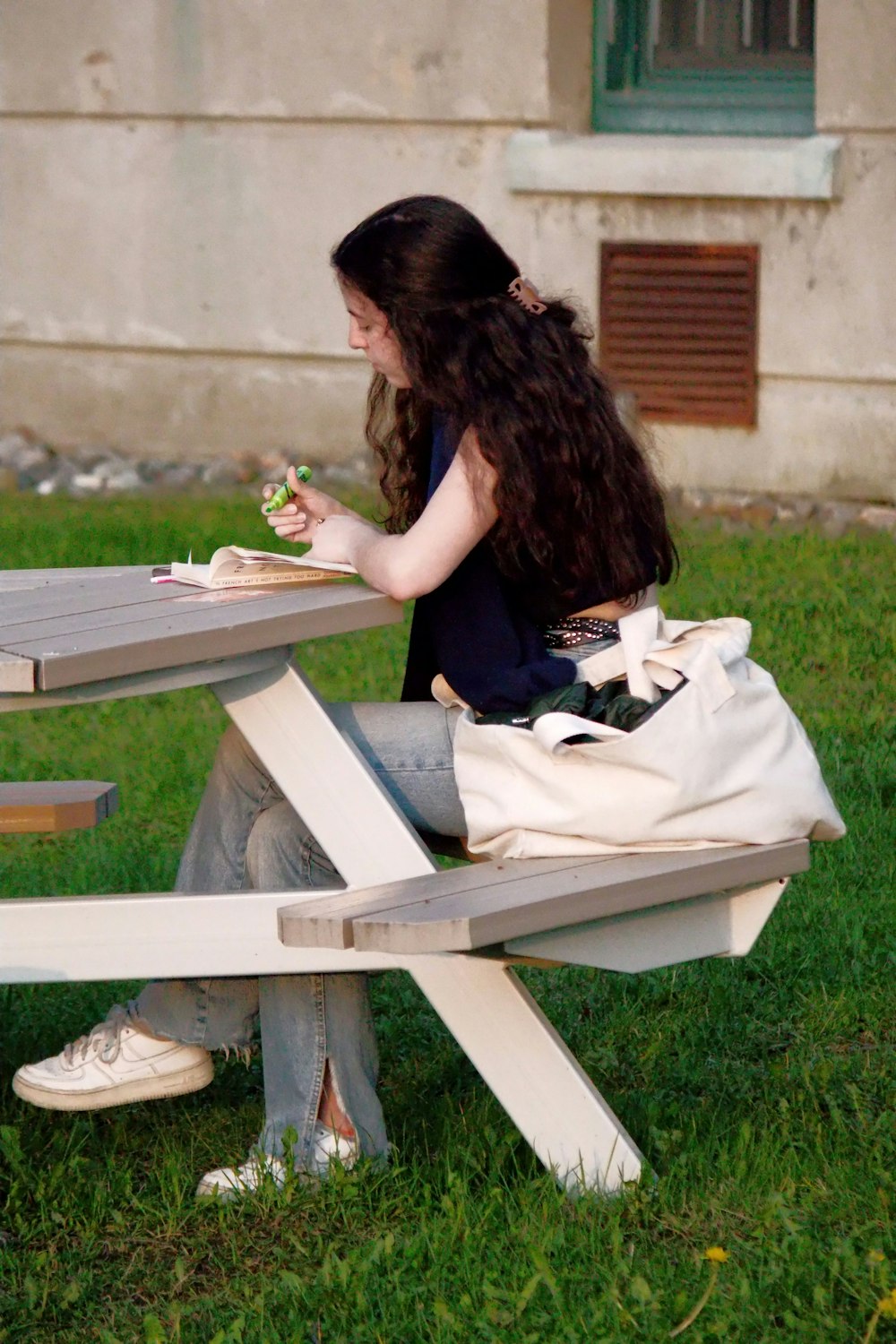 a woman sitting at a picnic table eating a sandwich