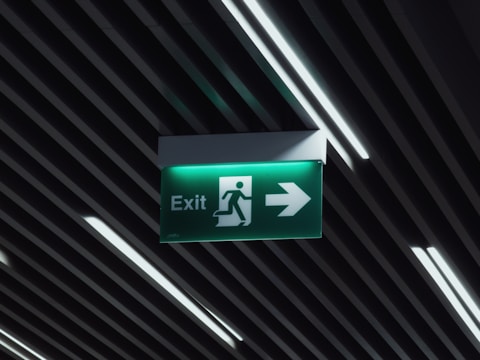 a green exit sign hanging from the ceiling