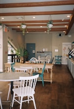 a restaurant with tables, chairs, and potted plants