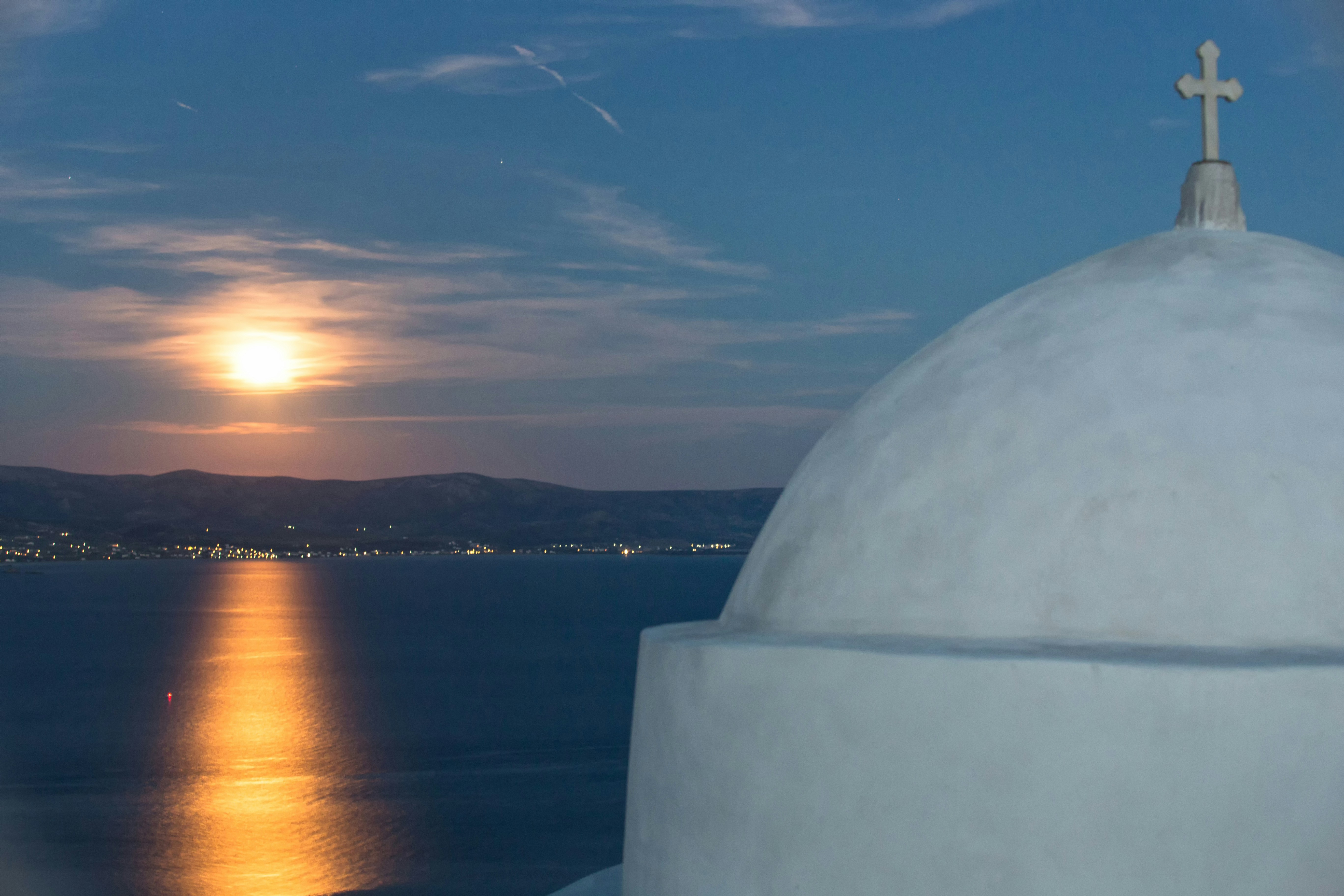 a cross on top of a building next to a body of water, 