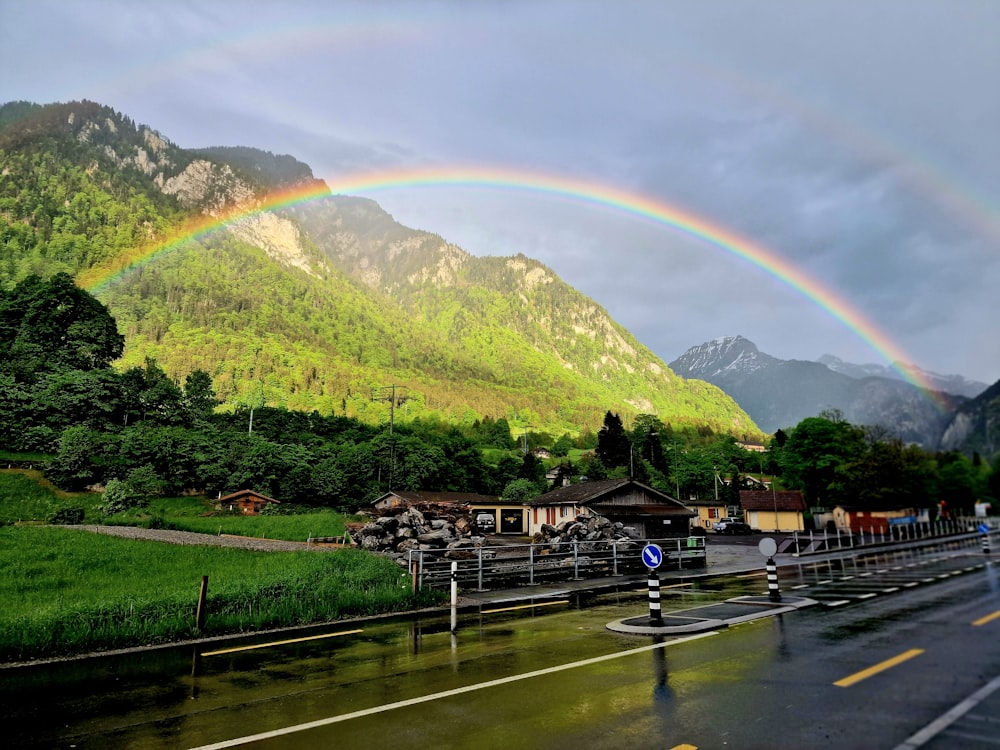 a rainbow appears over a mountain village in the rain
