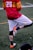 a man in a red and yellow uniform kicking a soccer ball