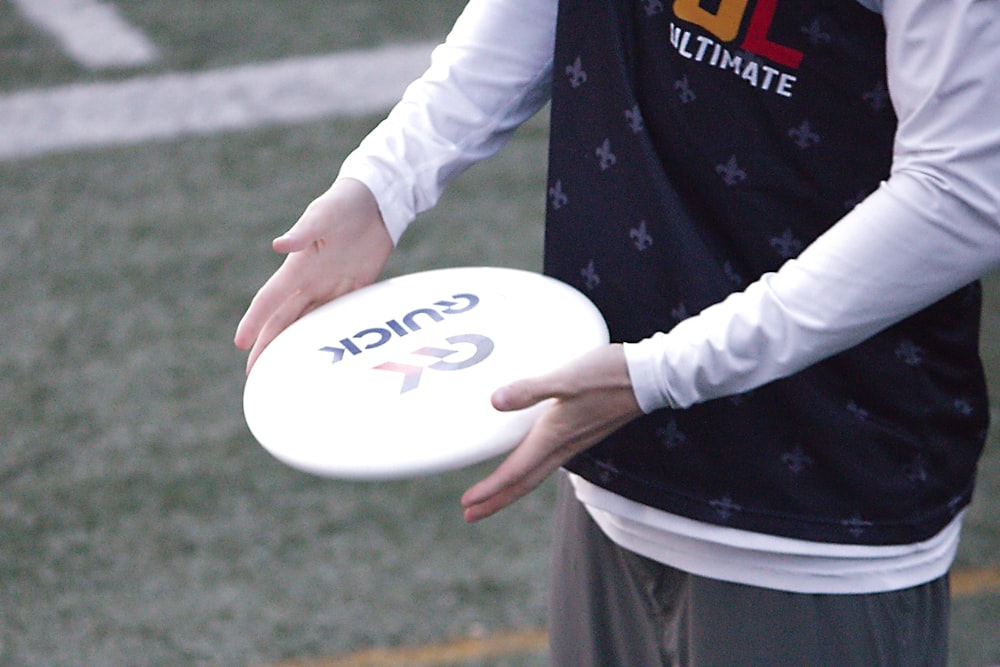 a man holding a white frisbee on top of a field
