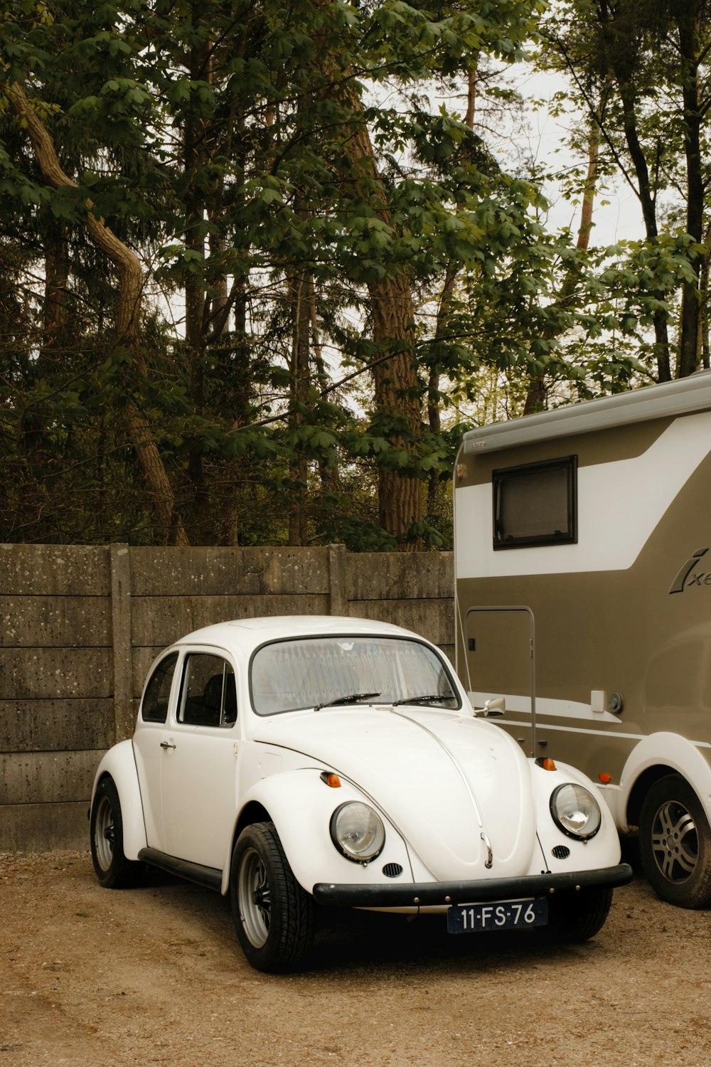 a white vw bug parked next to a trailer