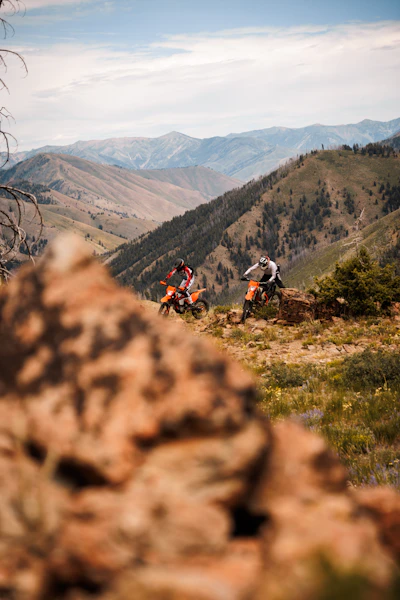 a couple of people on dirt bikes on a hill