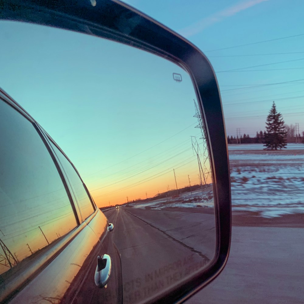 um espelho retrovisor em um carro refletindo um pôr do sol