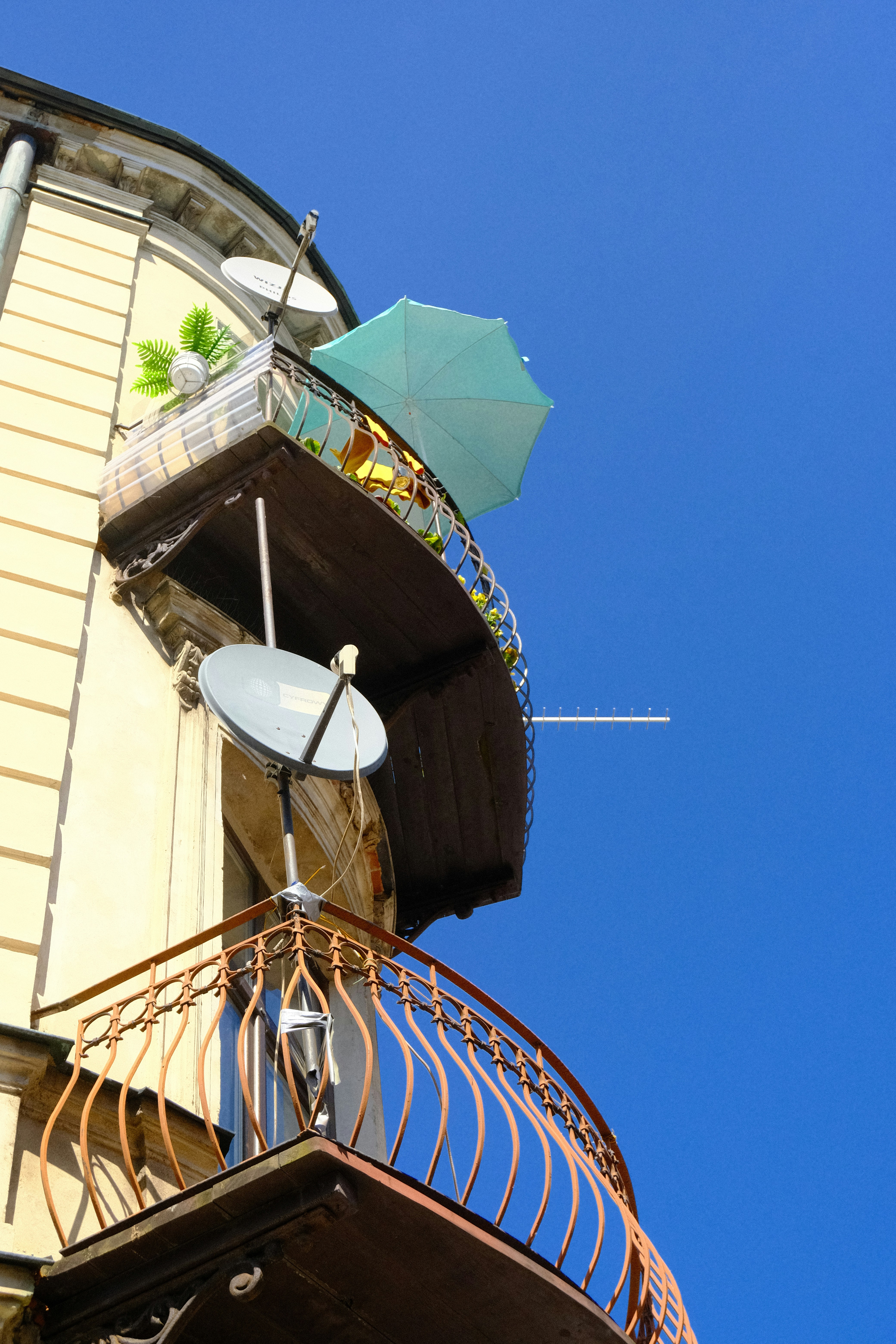 a tall building with a balcony and a green umbrella