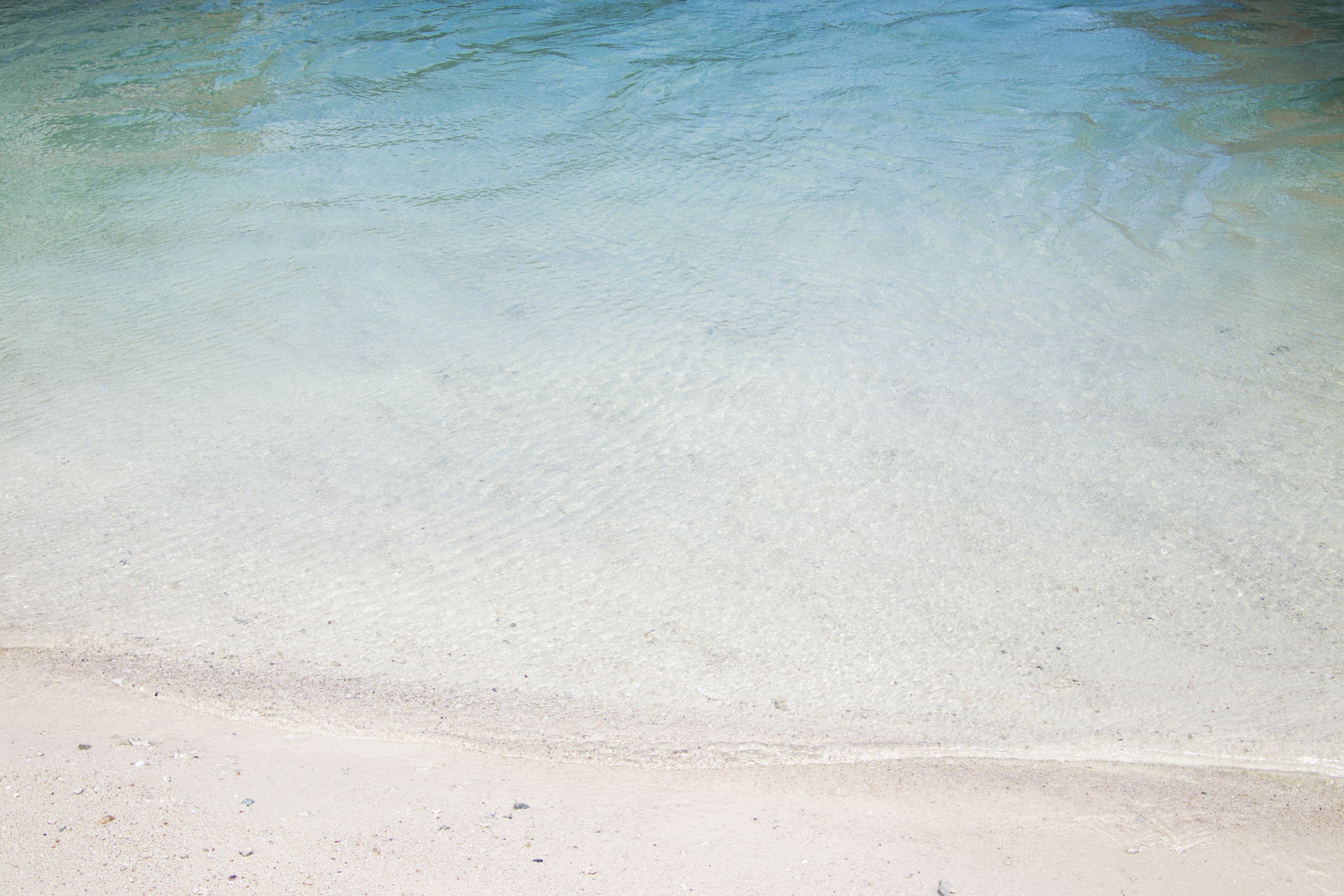 a man sitting on a beach next to a body of water