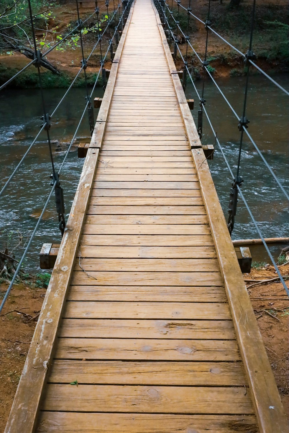 a wooden suspension bridge over a river in the woods