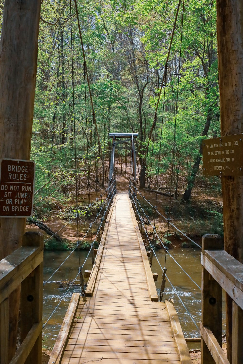 a wooden suspension bridge over a river in the woods