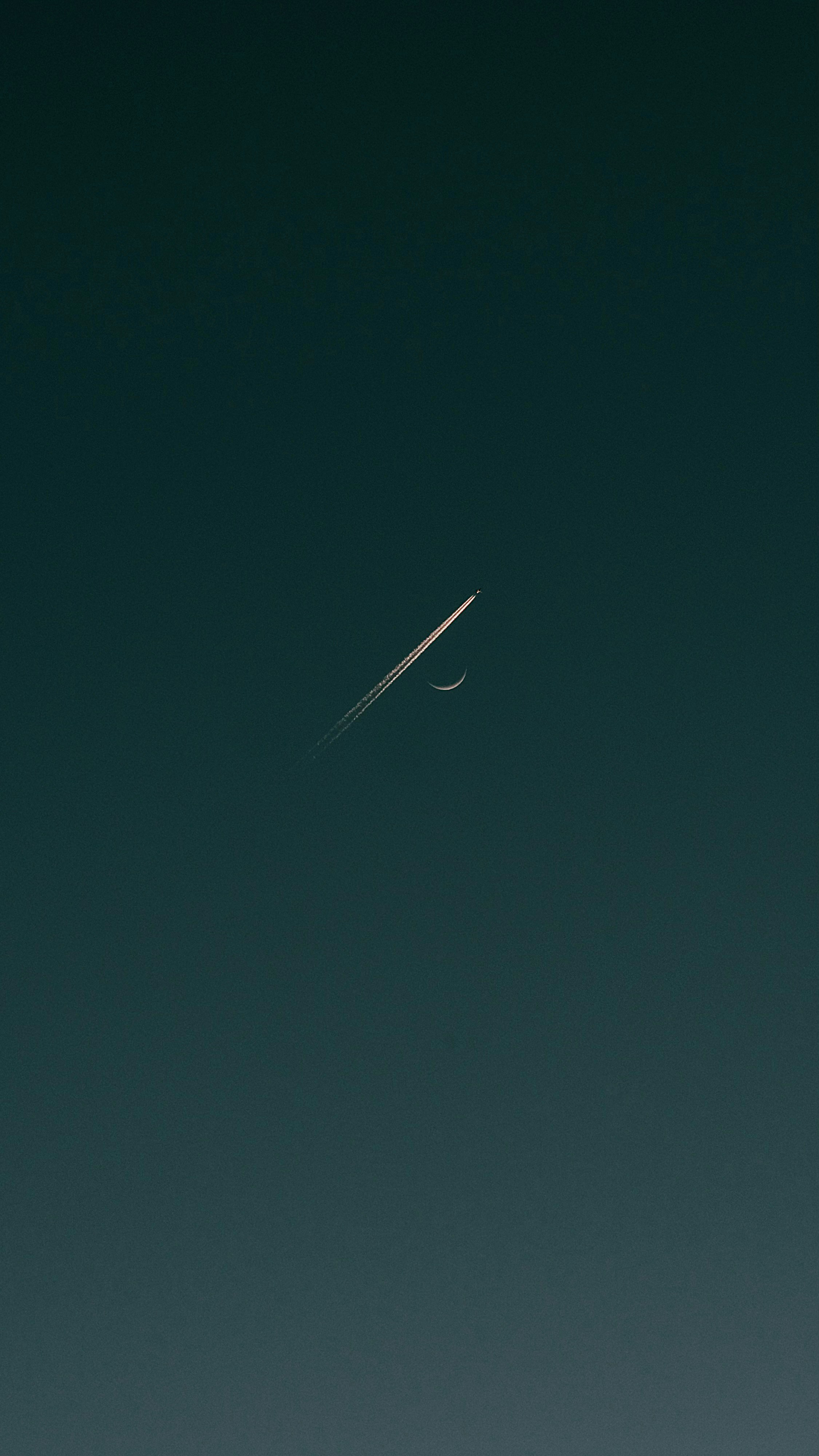 an airplane flying in the sky with a crescent moon