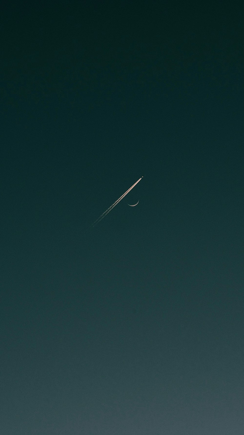 an airplane flying in the sky with a crescent moon