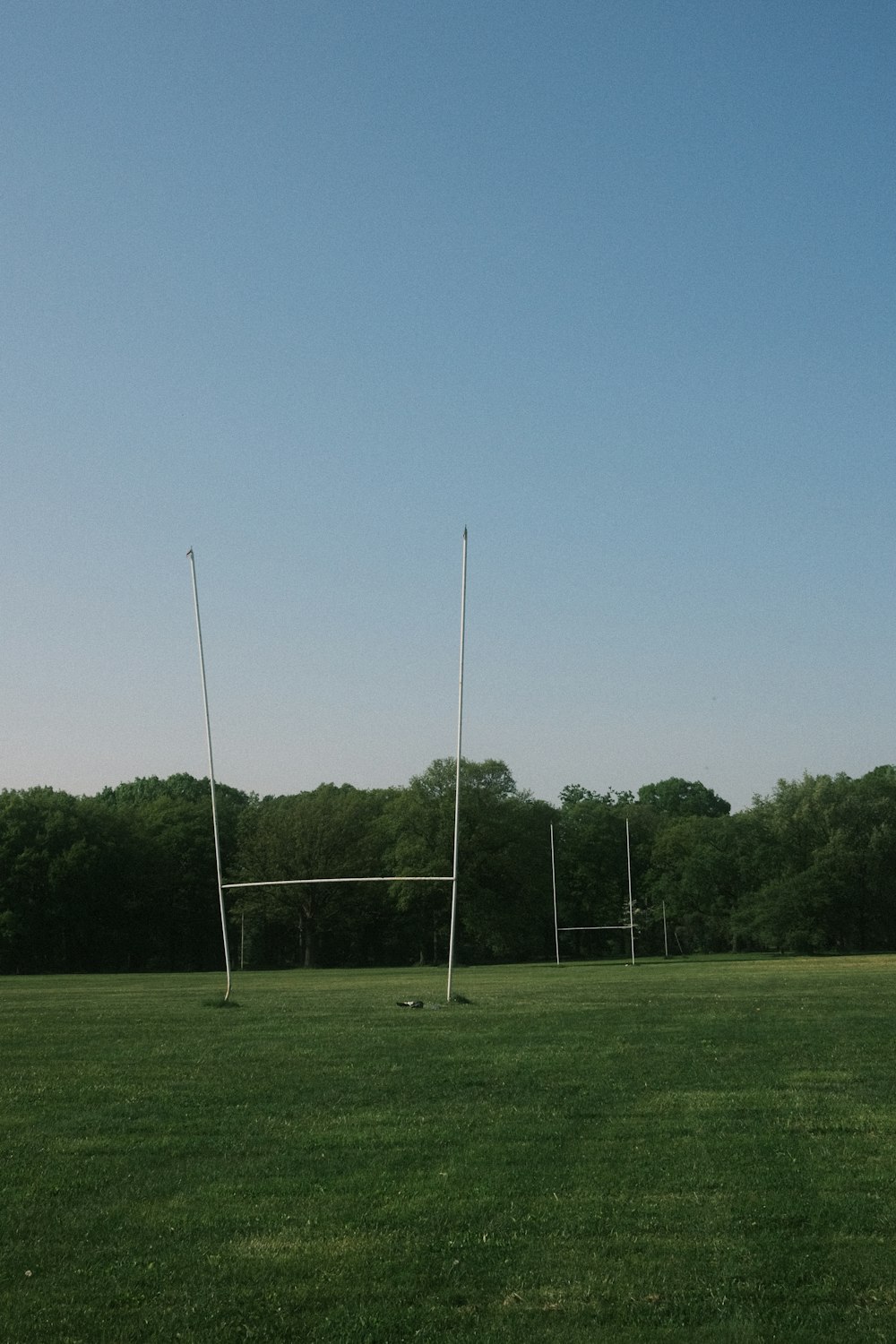 a soccer goal in a field with trees in the background