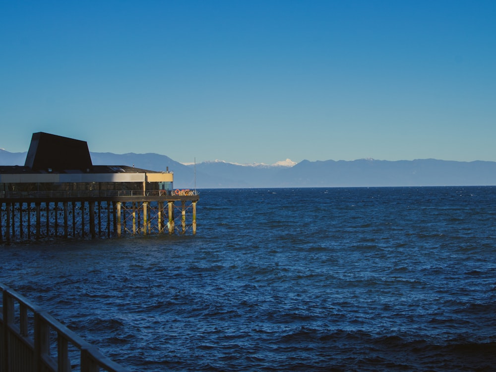 a pier in the middle of the ocean with mountains in the background