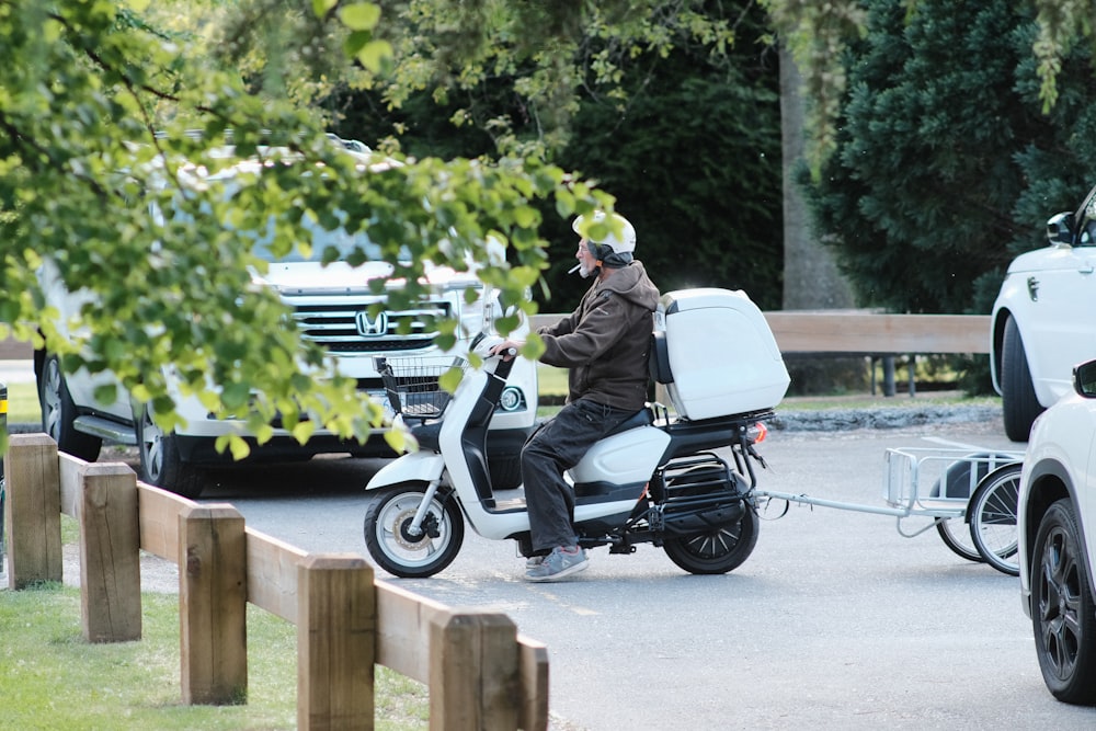a man riding a scooter with a trailer attached to it