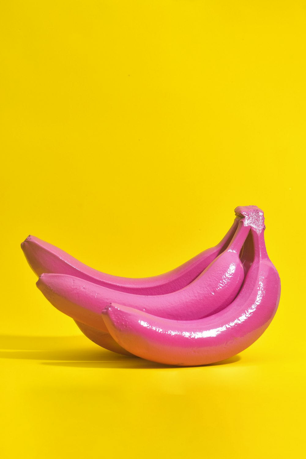a pink banana sitting on top of a yellow background