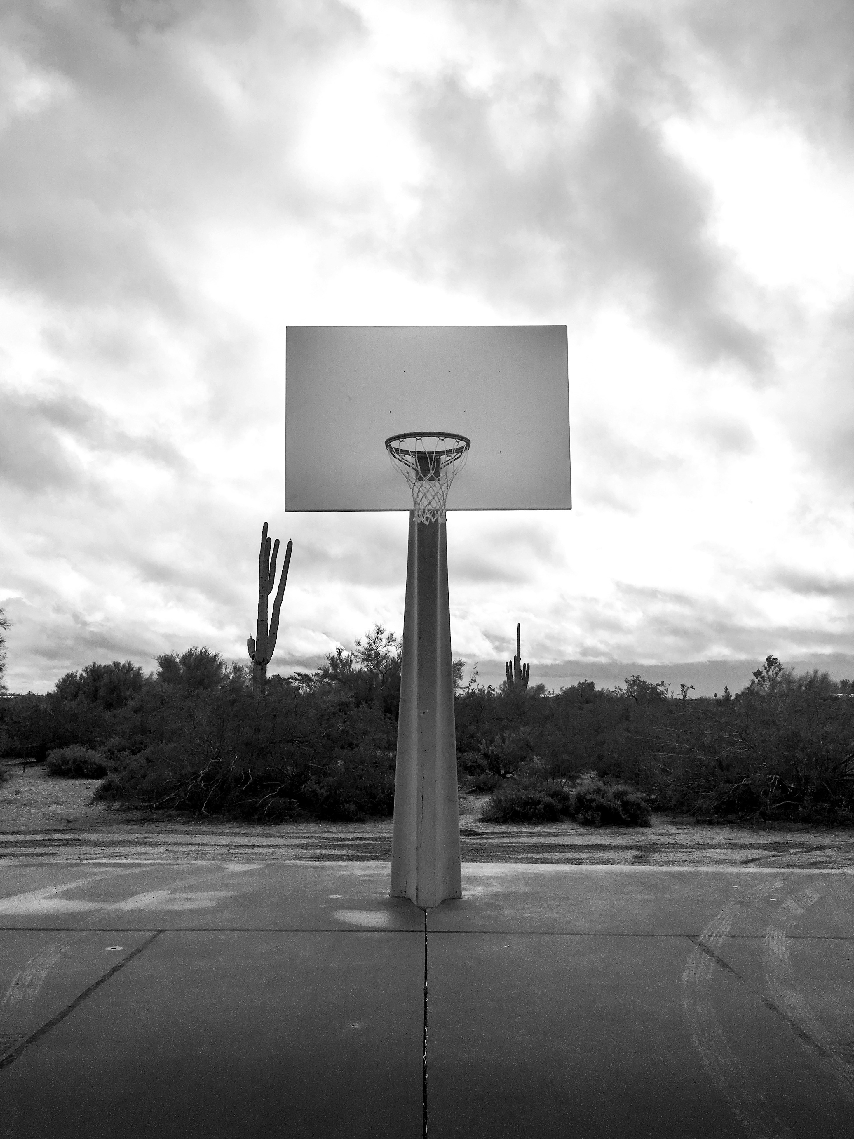 a basketball hoop in a parking lot with a sky background