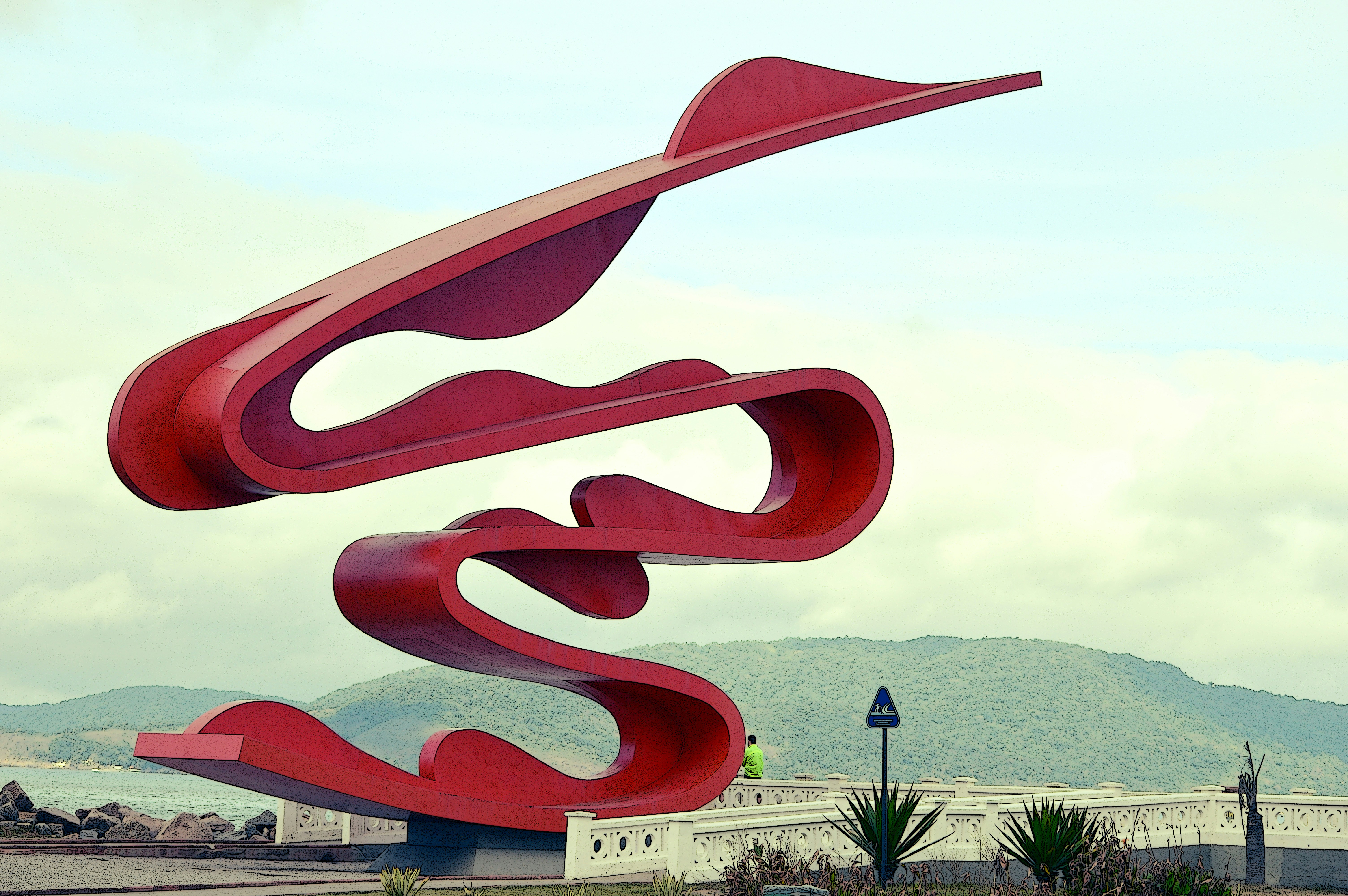 a large red sculpture sitting on top of a lush green field