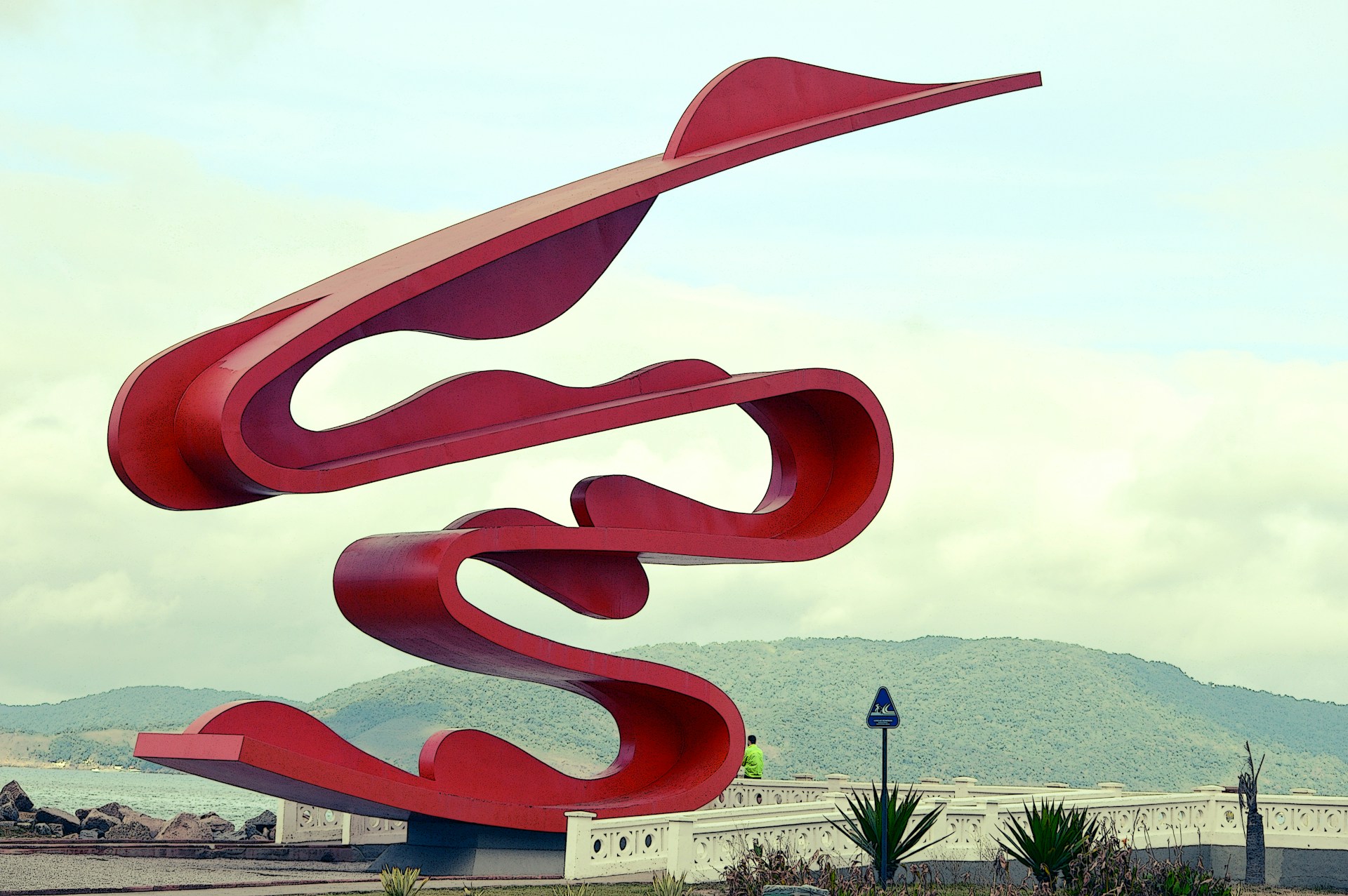 a large red sculpture sitting on top of a lush green field