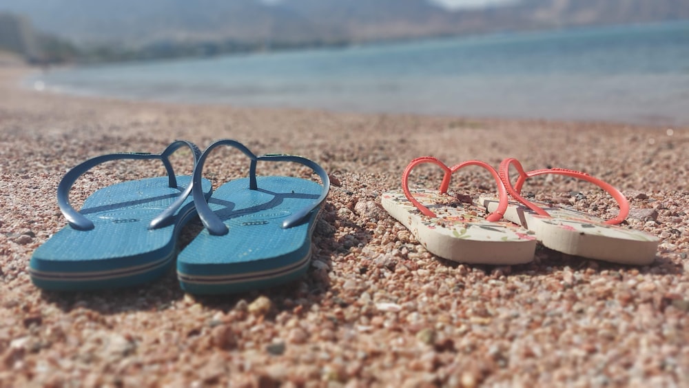 a pair of flip flops sitting on top of a sandy beach