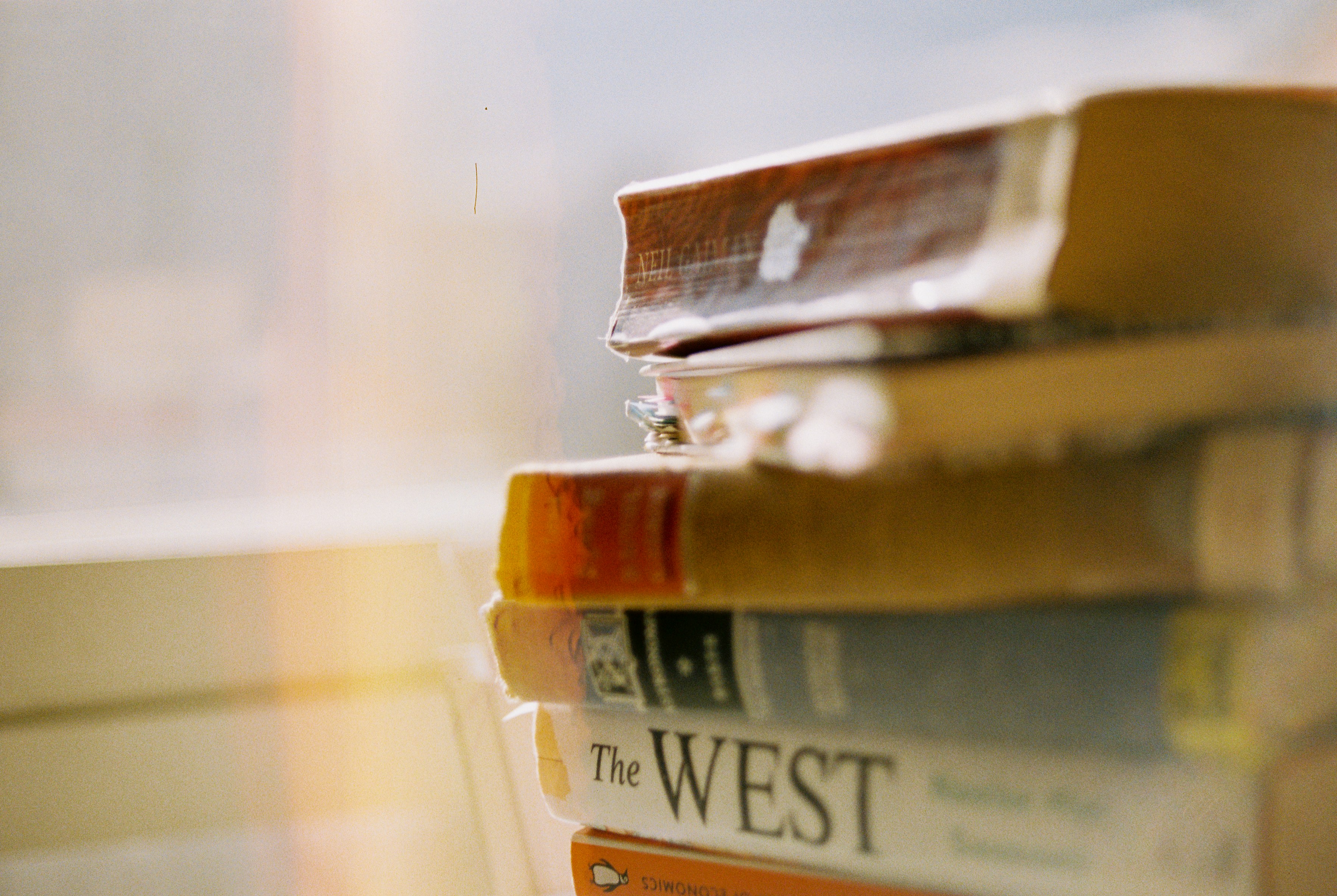 a stack of books sitting on top of a window sill