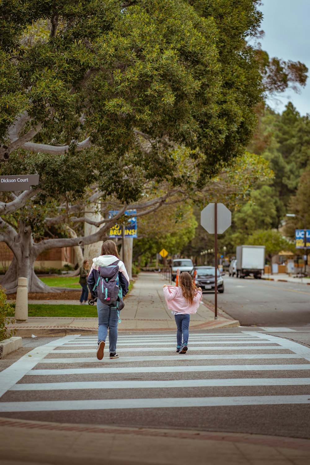two girls crossing the street in a crosswalk