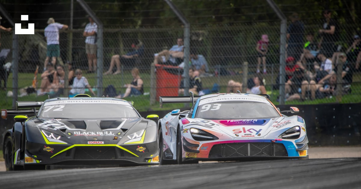 Two racing cars on a race track with spectators in the background photo ...