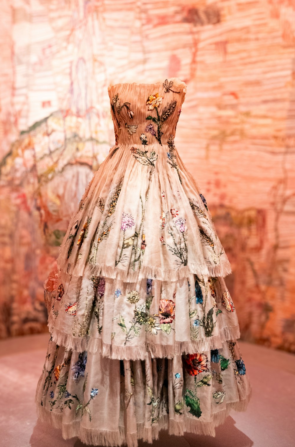 a dress is displayed on a pedestal in front of a wall