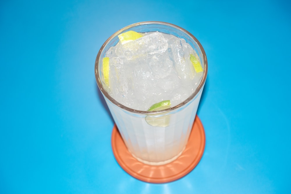 a drink with ice and lime on a blue background