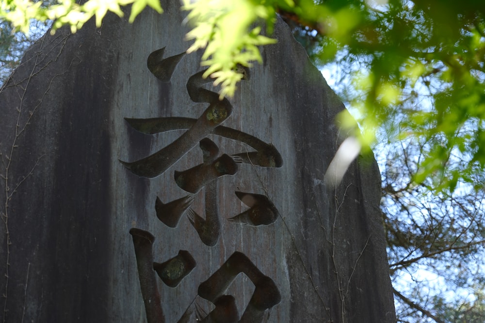 a large rock with writing on it and trees in the background