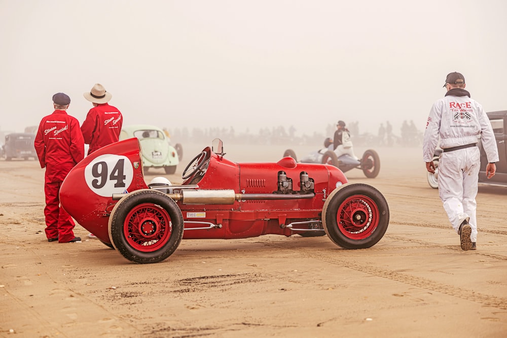 a red race car sitting on top of a dirt field