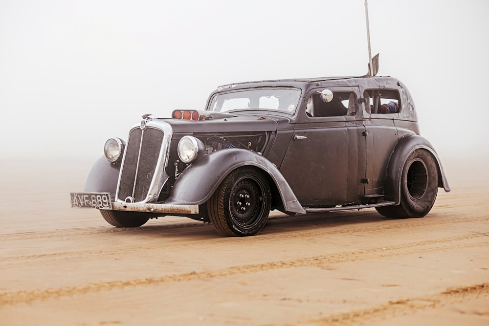 an old car is parked in the sand