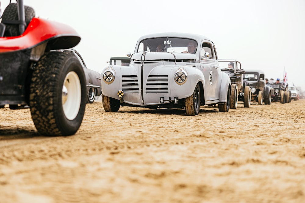 a row of old cars sitting on top of a dirt field