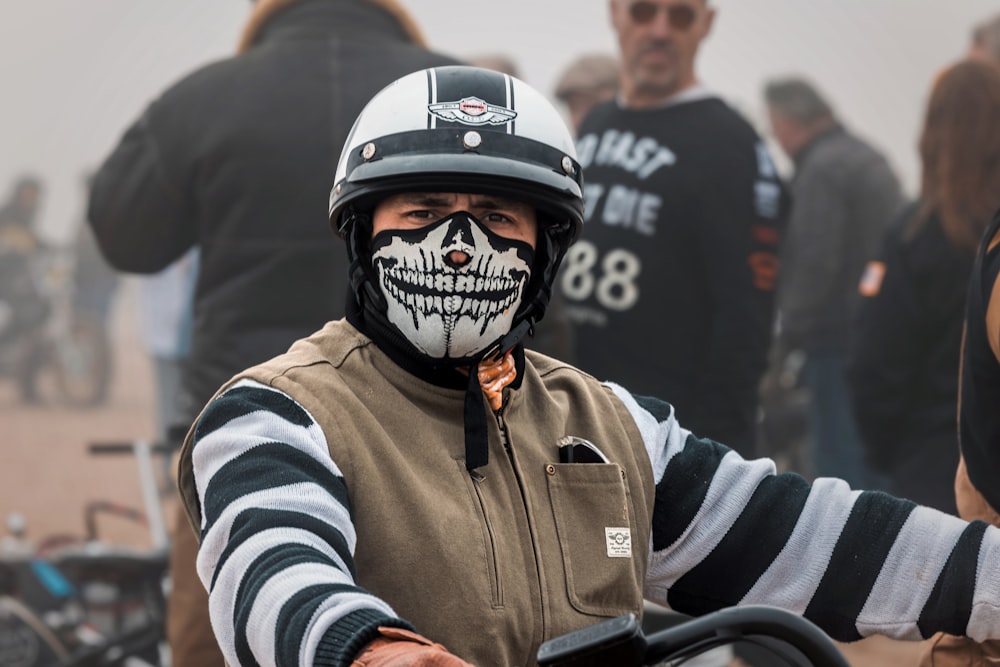 a man with a skull painted on his face riding a motorcycle
