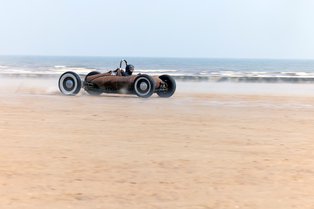 a man driving a buggy on a sandy beach