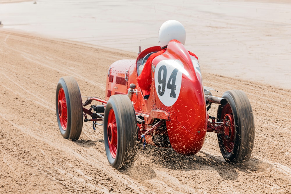 a red race car driving down a dirt road