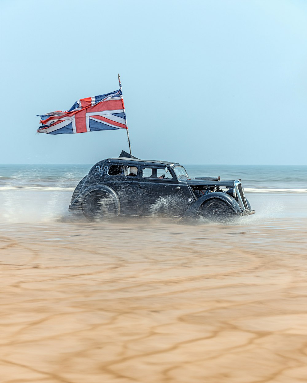 a car driving through the sand with a flag on top of it