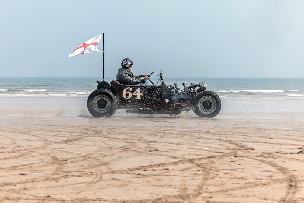 a man driving an old fashioned car on the beach