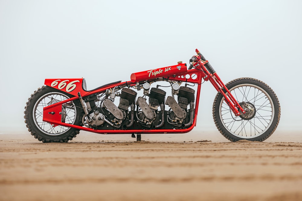 a red motorcycle parked on top of a dirt field
