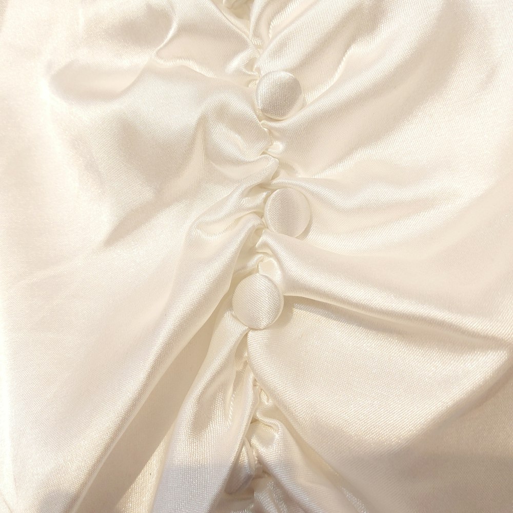 a close up of a white fabric with buttons