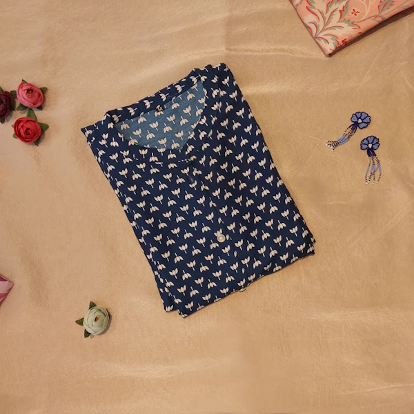 Printed kurta and earrings laid out on a bed